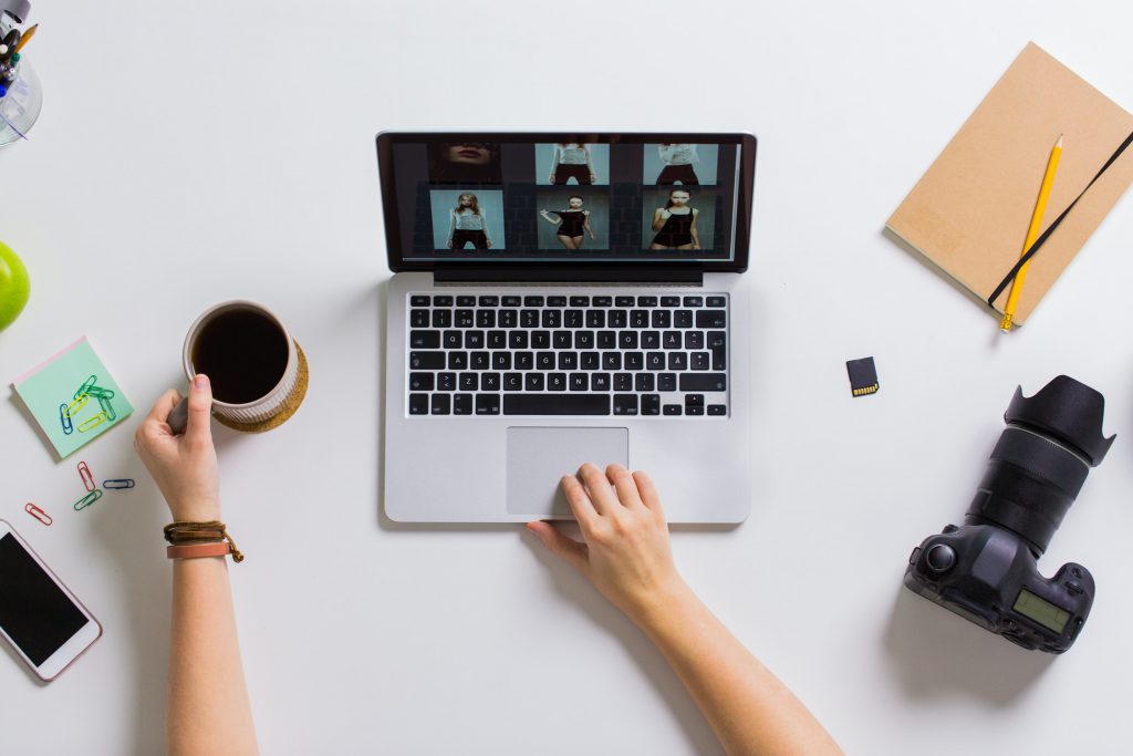 woman hands with camera working on laptop at table